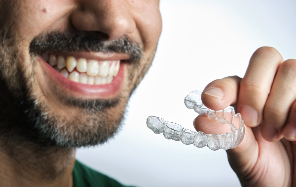 close up of a man holding clear aligners