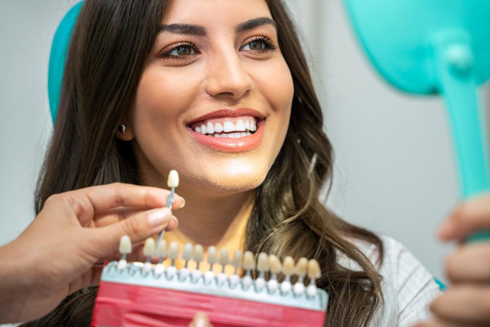 woman sitting in a dental chair while holding a mirror