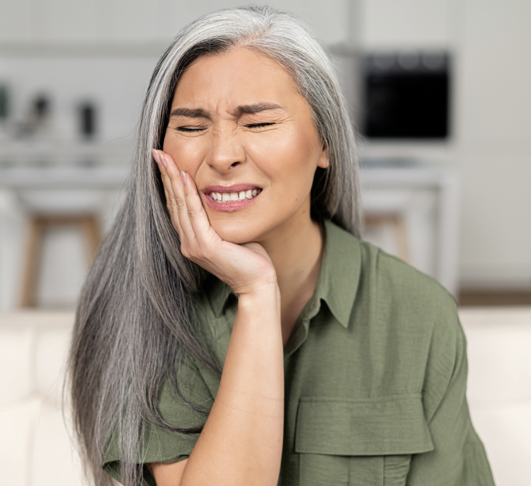woman holding her right cheek