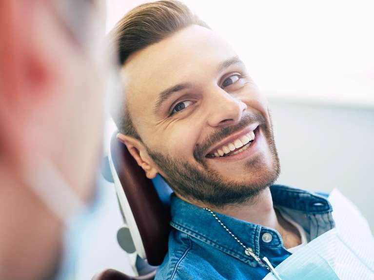 man sitting in a dental chair while smiling